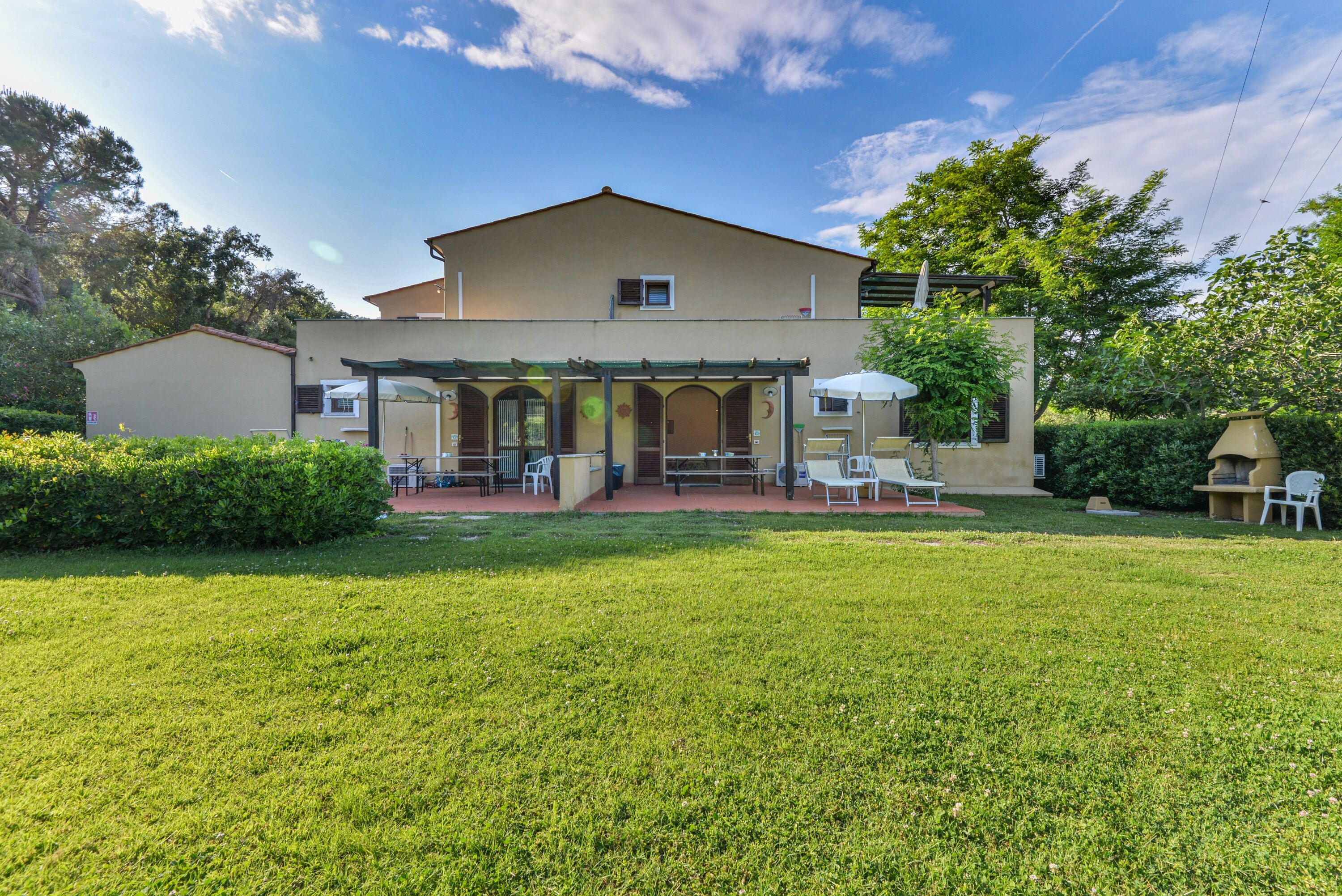 A two-story building with a covered patio area, a lawn, and a garden.