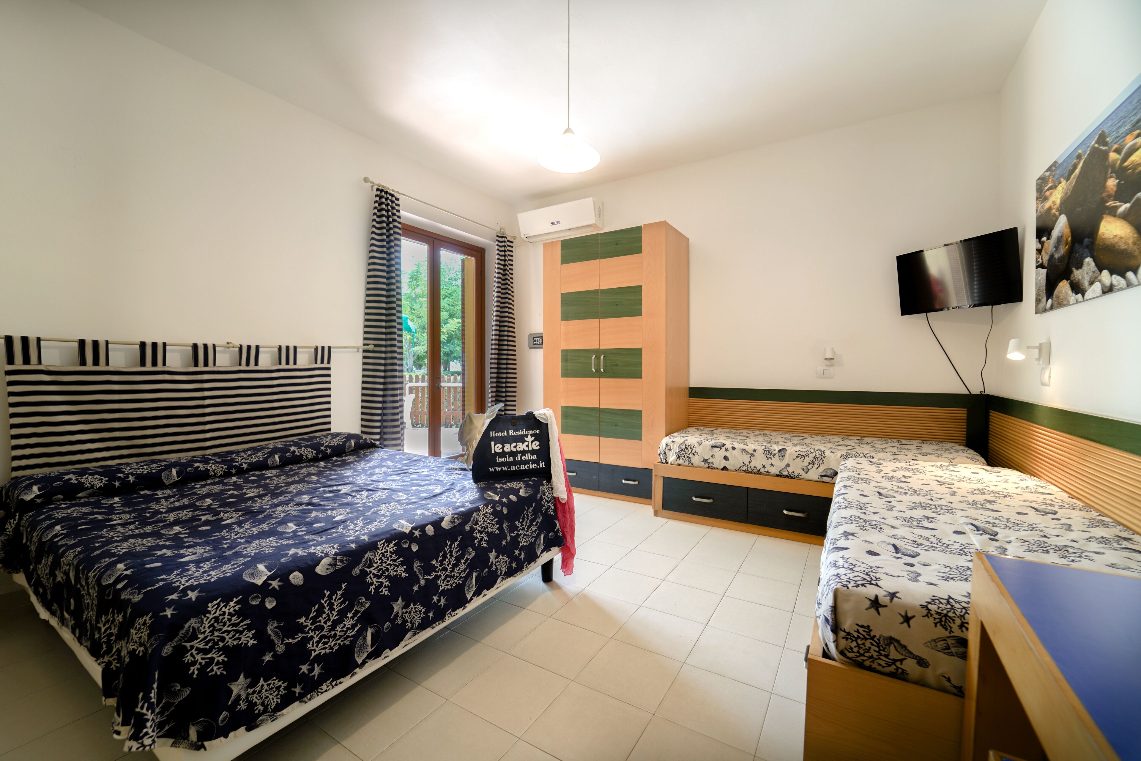 A bedroom with a large bed, a smaller bed, a wardrobe, a TV, and a desk.