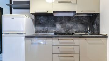 A modern kitchen with white cabinets, a black marble backsplash, and a built-in stove.