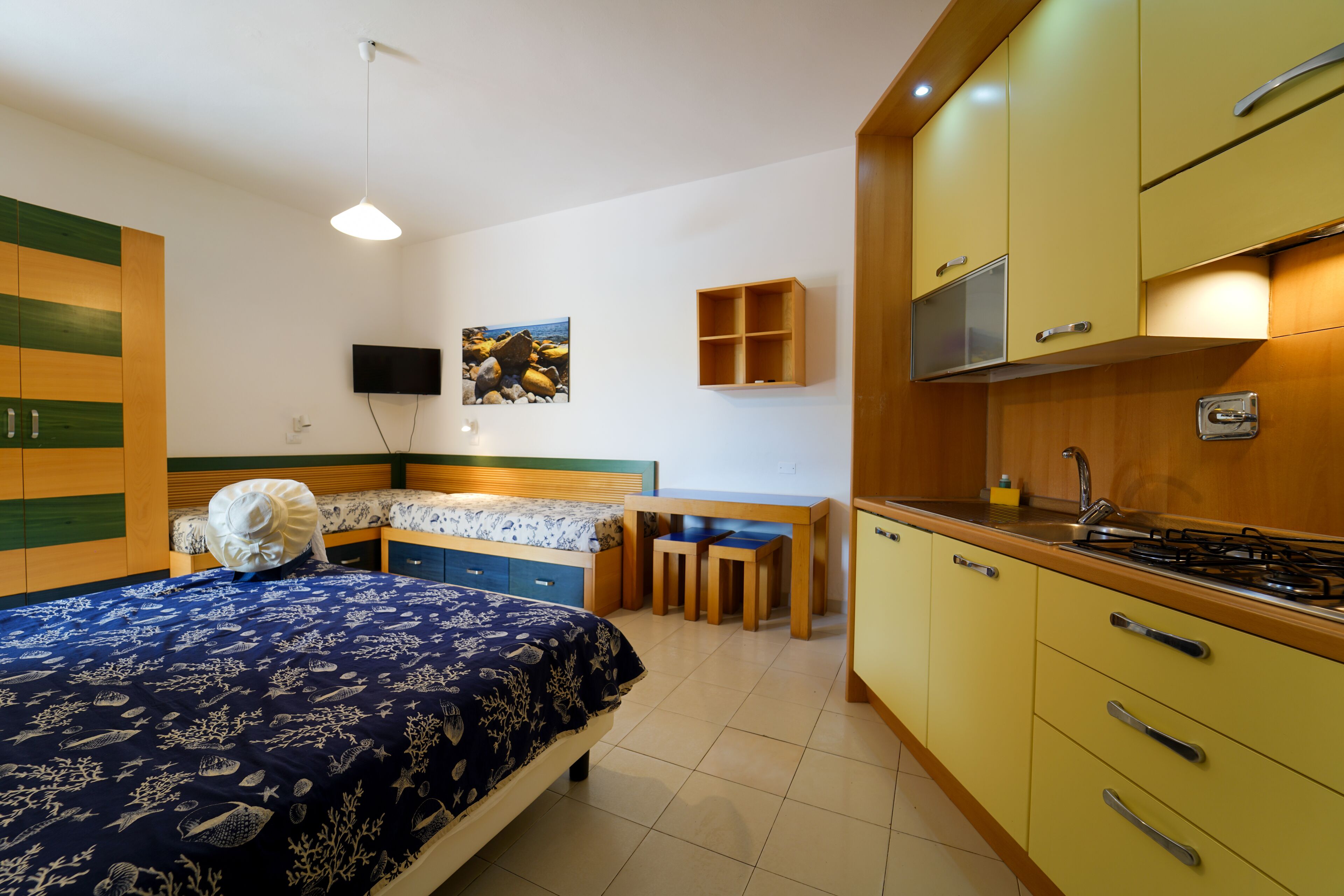 A compact bedroom with a bed, bedside table, and a small desk with a chair.