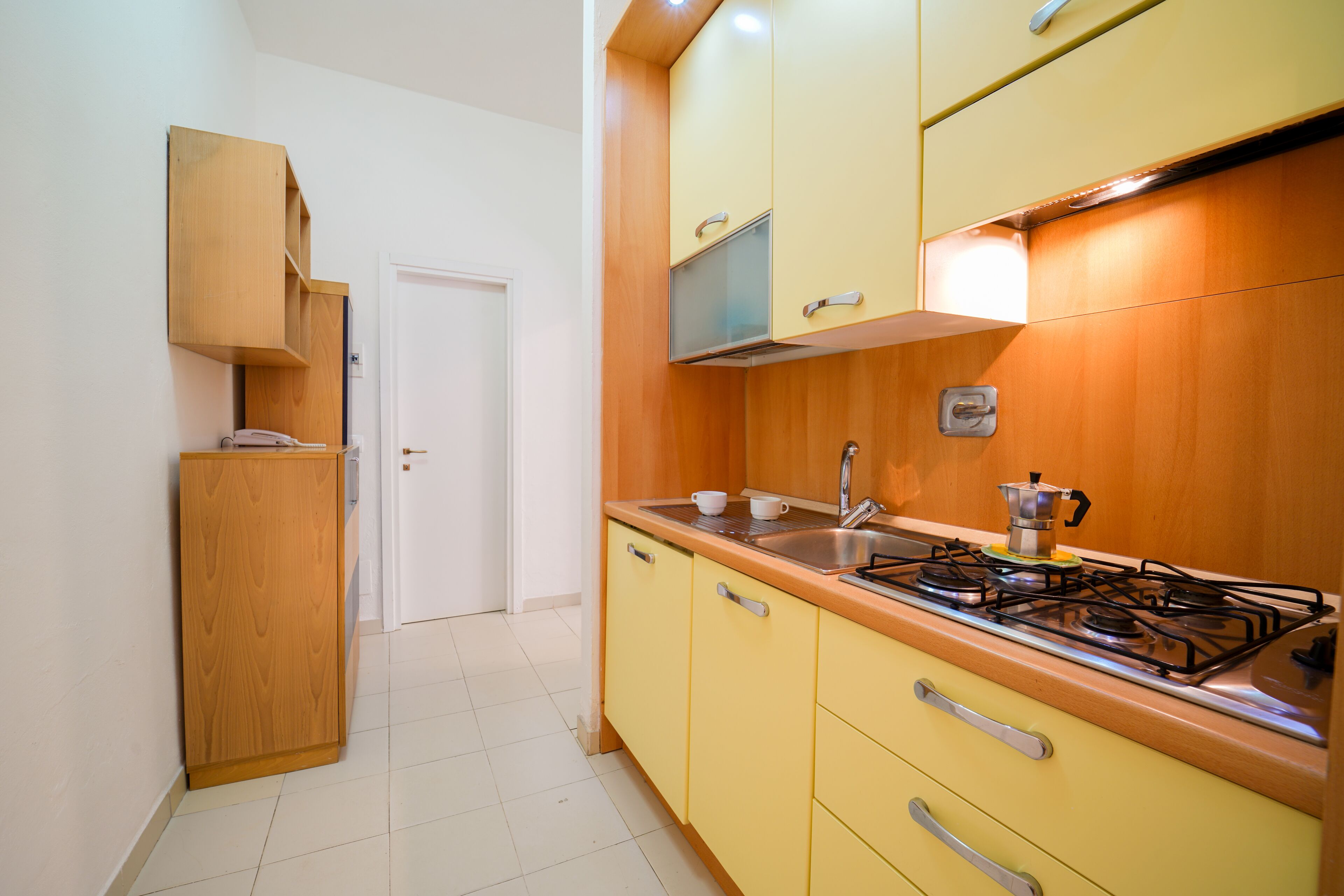 A kitchen with wooden cabinets, a stove, and a sink.