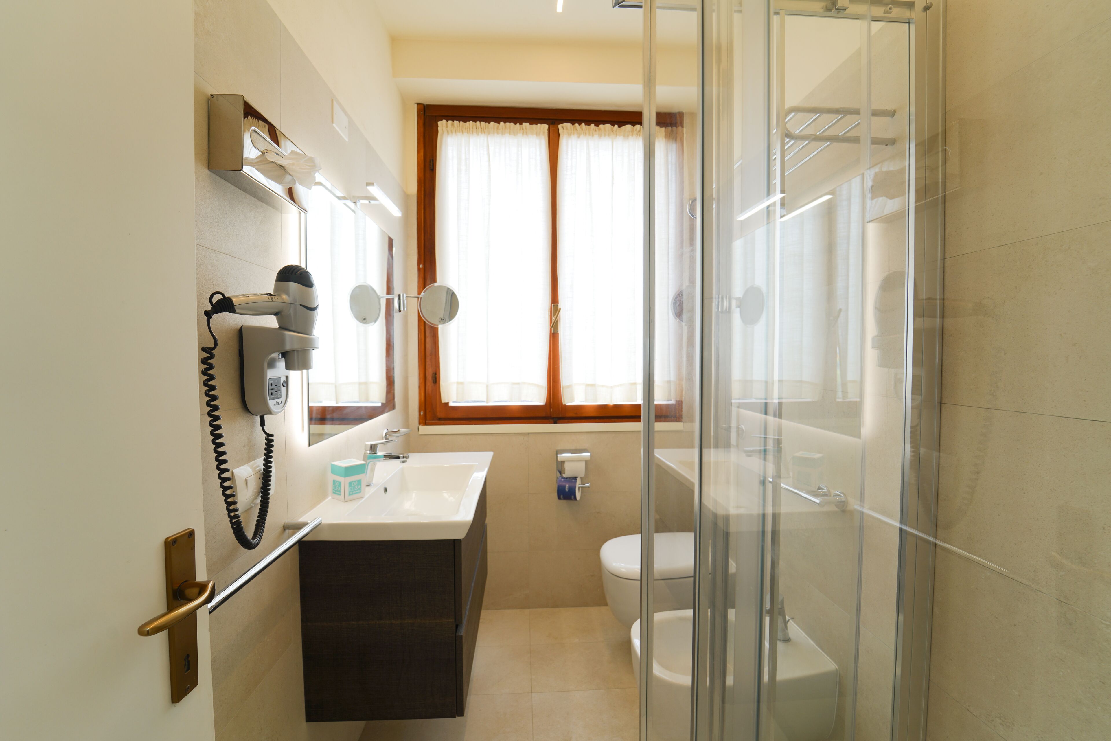 Ein Badezimmer mit Duschkabine aus Glas, Waschbecken mit Spiegel und Toilette.