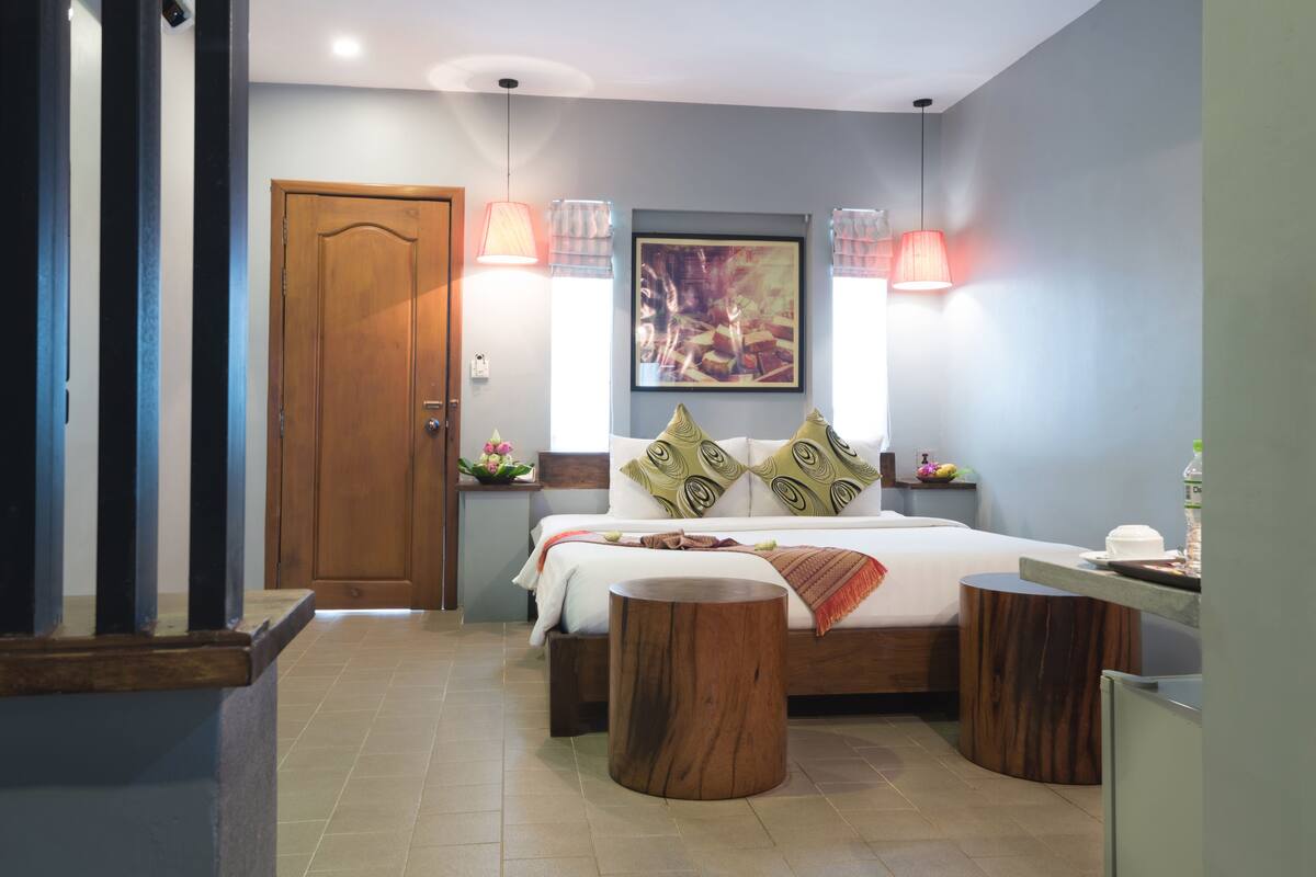 A modern bedroom with a wooden bed, two bedside tables, a large painting on the wall, and a door.