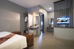 Camera d'albergo con un letto, una scrivania, una televisione e un bagno visibile attraverso una porta aperta.