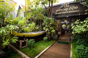 Un rigoglioso giardino con un sentiero in legno che conduce a un edificio con la scritta "HEAVENANGKOR RESIDENCE".
