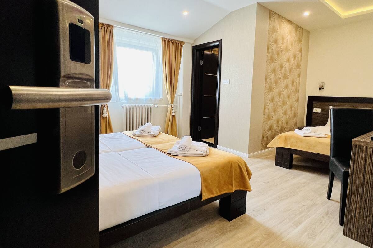 Quarto de hotel com duas camas, uma escrivaninha e um guarda-roupa.