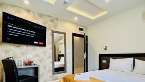 Habitación de hotel con una cama, un escritorio, una silla, un televisor montado en la pared y un espejo.