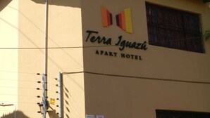 The Terra Iguazi Apt Hotel sign with a simple facade and a window with a metal grill. - Terra Iguazú Apart Hotel (Puerto Iguazú)