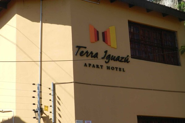 The Terra Iguazi Apt Hotel sign with a simple facade and a window with a metal grill.