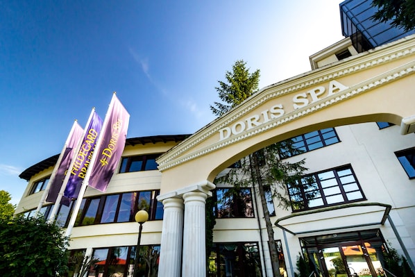 The exterior of Doris Spa with a clear entrance, large windows, and three purple banners.