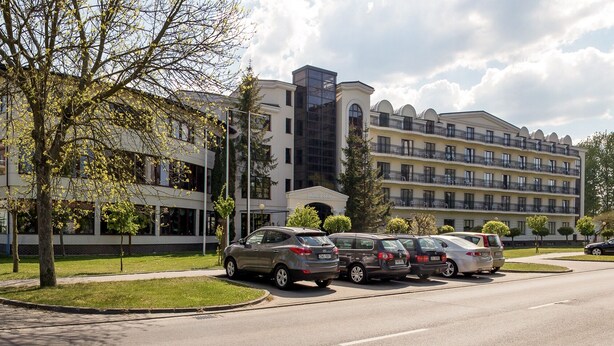 A hotel with multiple floors, a parking lot, and a building with a modern architectural style. - Doris Spa (Kolobrzeg)