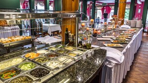 Un bufé con diversas opciones de comida y una larga mesa dispuesta para comer.