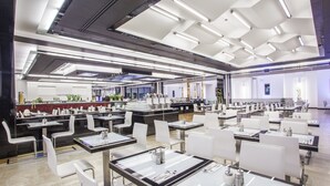 A modern dining area with multiple tables and chairs, overhead lighting, and a clean, organized layout.
