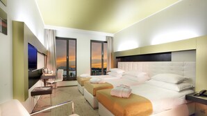 A modern hotel room with a large bed, two bedside tables, a desk, and a chair.