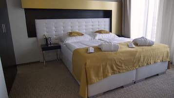 A hotel room with a large bed, a nightstand, and a minibar.