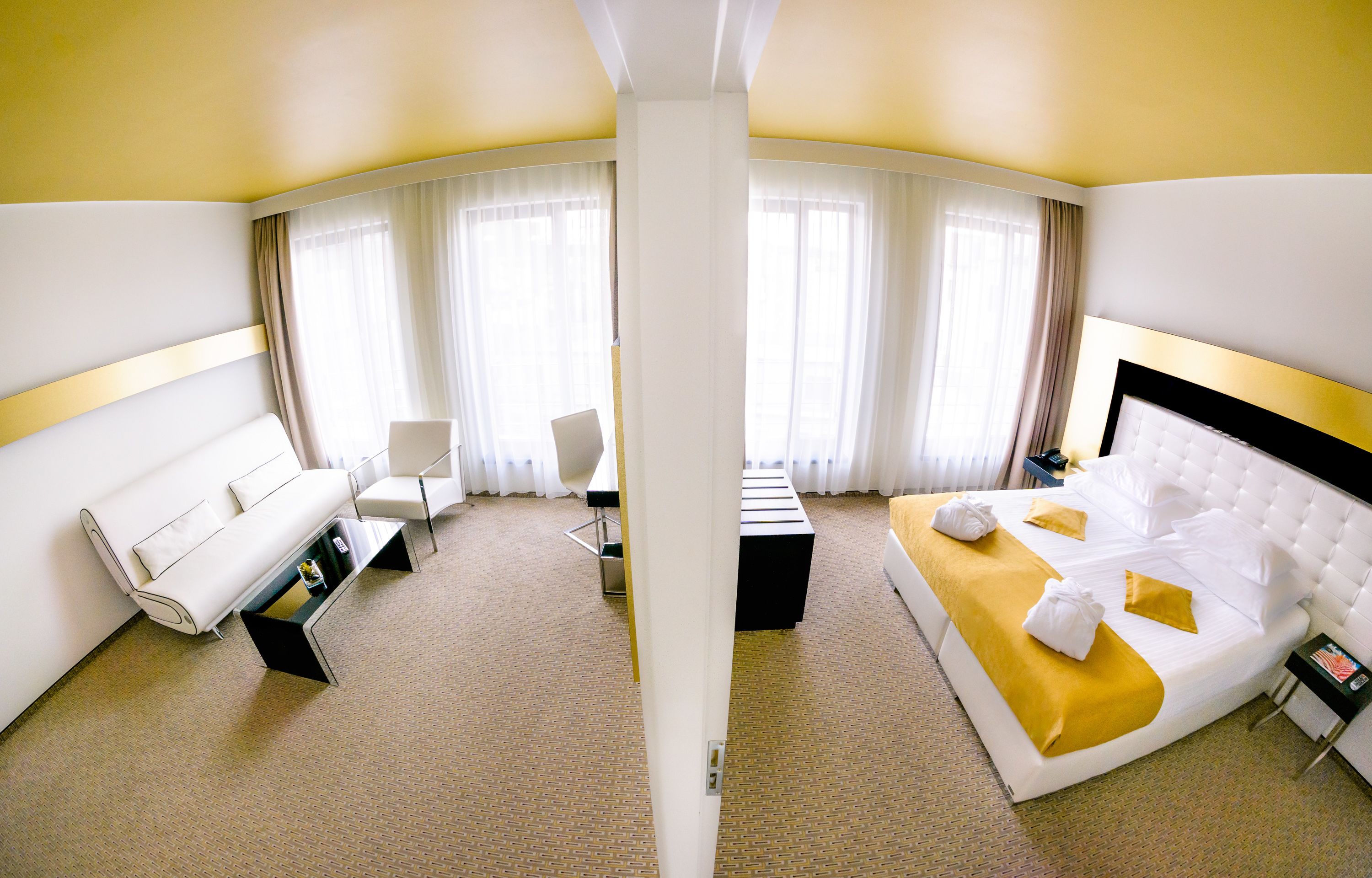 Una camera d'albergo con un letto bianco, un divano, una scrivania e una sedia.