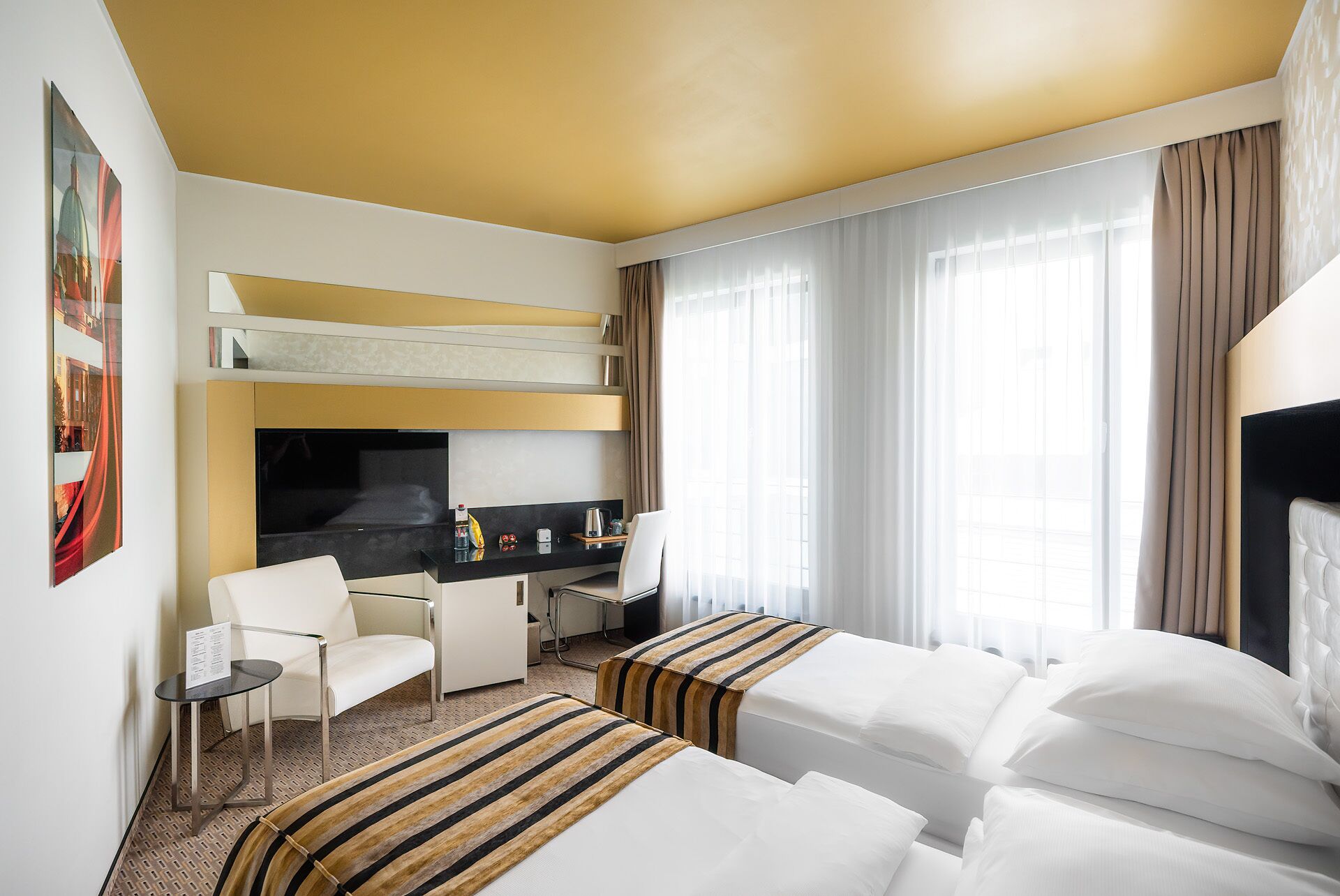 A hotel room with a bunk bed, a desk, a chair, and a small table.