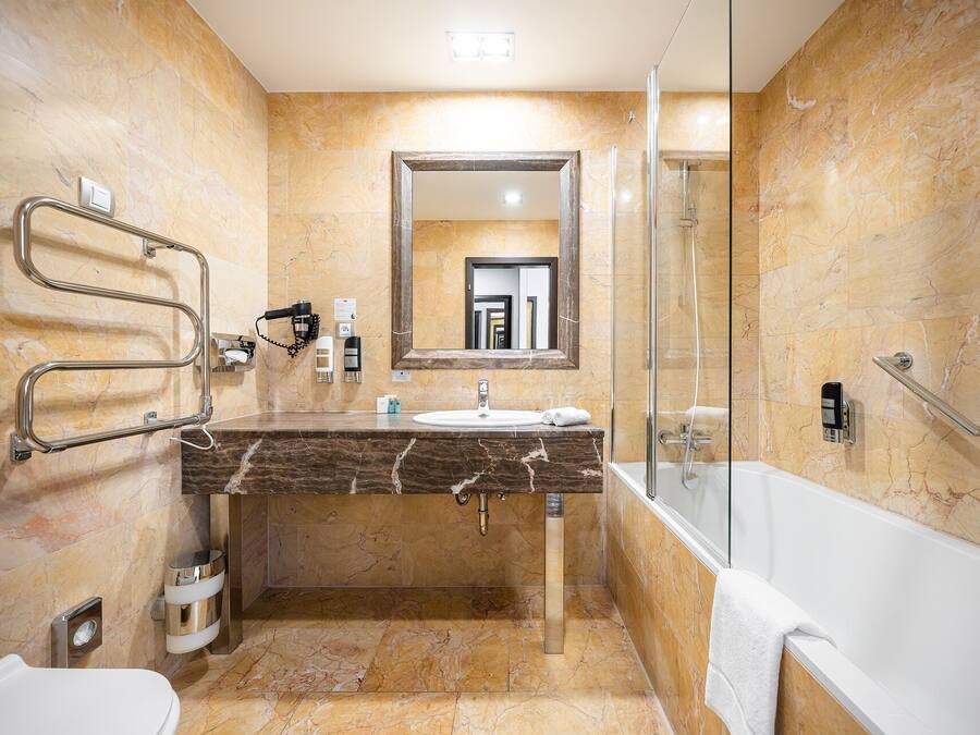 A modern bathroom with a marble vanity, a glass shower enclosure, and a hand dryer.