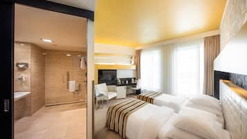 Una habitación de hotel con ducha, escritorio, cama y ventana con cortinas.