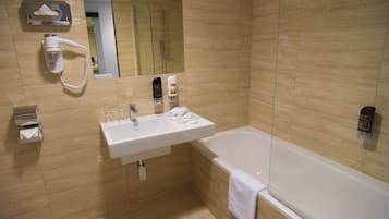 A modern bathroom with a sink, mirror, and bathtub.