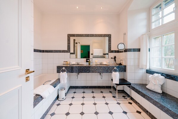 Un baño con lavamanos doble, bañera y un espejo grande.