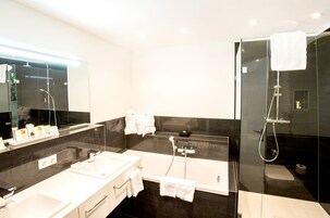 Un baño moderno con un espejo grande, una bañera, una ducha e inodoro.
