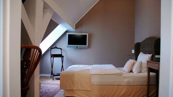 A bedroom with a bed, a chair, a television, and a view of the sky.