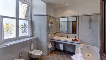 A modern bathroom with two sinks, a bathtub, and a toilet.