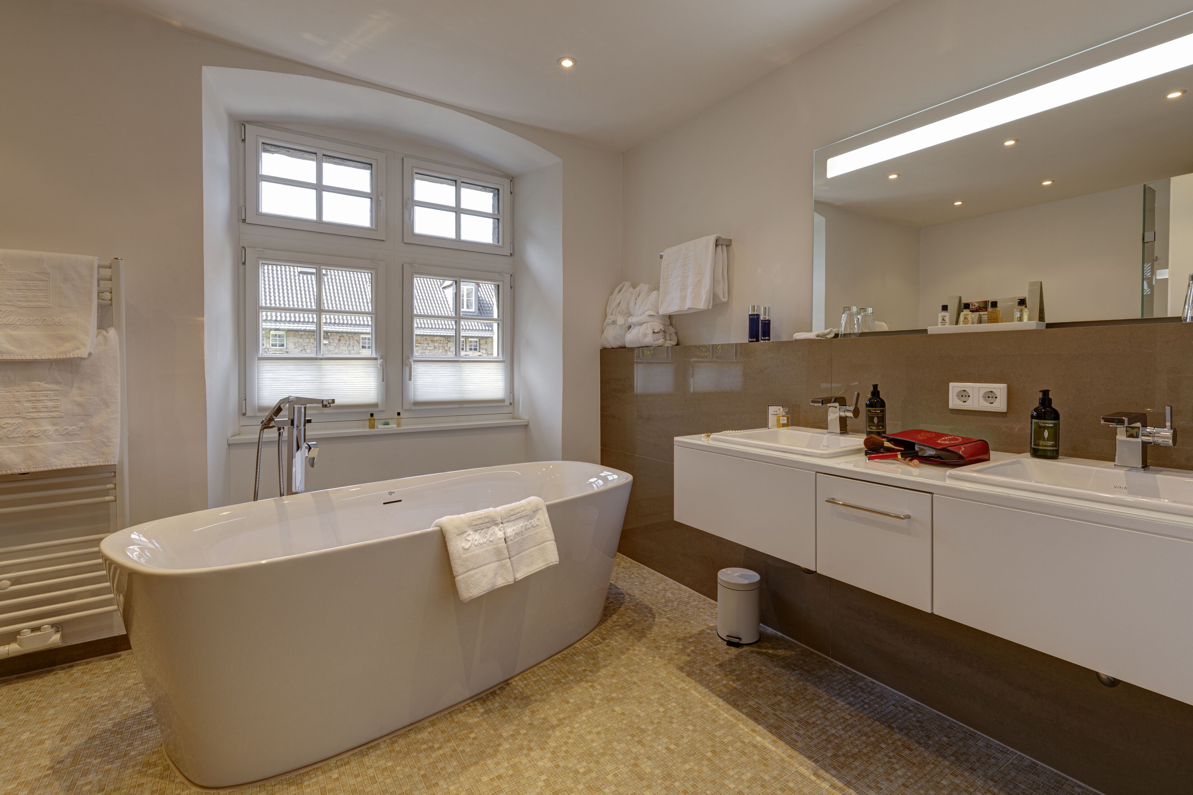 A modern bathroom with a freestanding bathtub, a large mirror, and a vanity with a countertop.