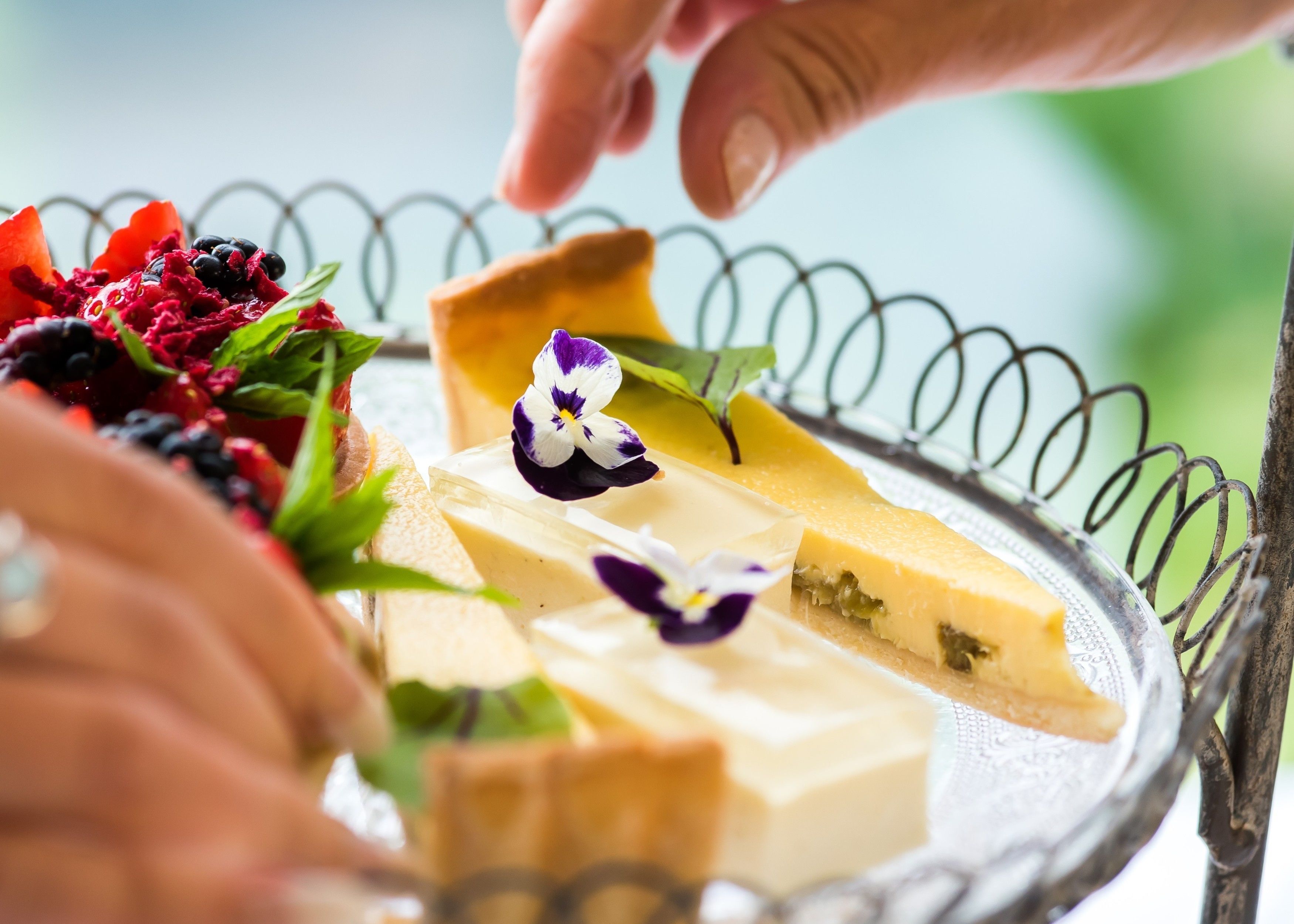 Un plateau de desserts avec divers types de sucreries et une main qui tend vers une part.