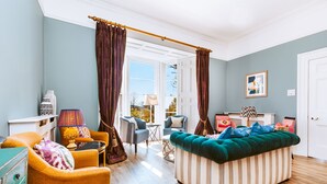 A living room with a sofa, chairs, a table, and curtains. - The Horn of Plenty (Tavistock)