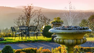 A garden with a fountain, a bench, and a table.