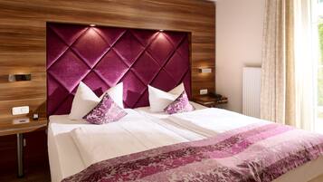 A hotel room with a large bed, a wooden headboard, and a nightstand with a lamp.