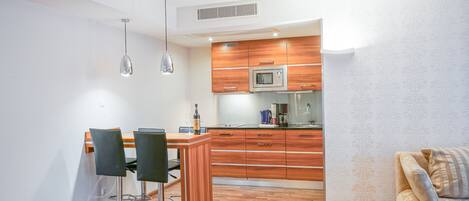 Una cucina moderna con mobili in legno, un forno a microonde e una macchina da caffè. C'è un'area pranzo con due sedie e un tavolo.