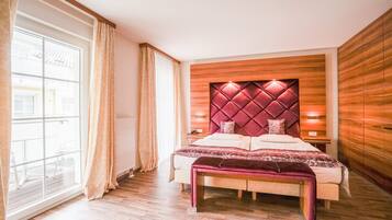 A bedroom with a large bed, wooden headboard, and a view of the outside through a window.