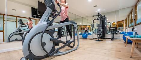 A modern gym with a stationary bike, exercise balls, and various fitness equipment.