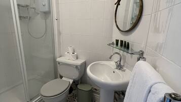 A bathroom with a shower, toilet, sink, and a mirror.
