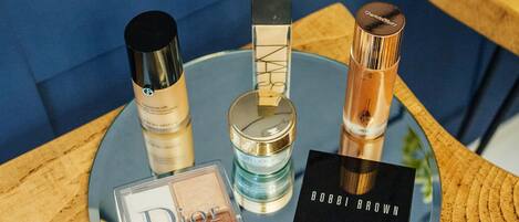 Un espejo redondo con varios productos de cosmética sobre una mesa de madera.