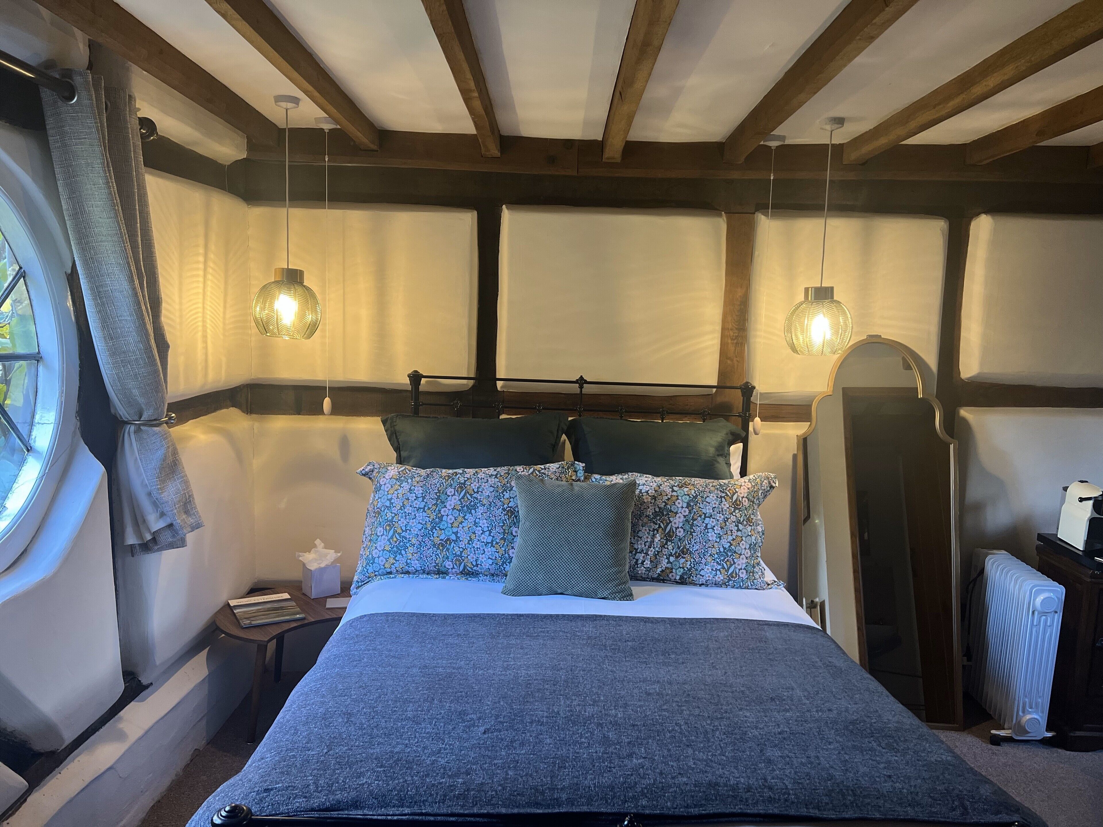 Une chambre à coucher avec un lit, deux lampes de chevet, une fenêtre avec des rideaux et un radiateur.