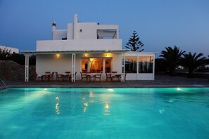 A modern house with a swimming pool, outdoor seating, and a covered patio. - New Aeolos Hotel (Mykonos)