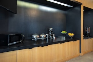 A modern kitchen with a black countertop, stainless steel appliances, and wooden cabinets. - Aloft by Marriott Oklahoma City Downtown - Bricktown (Oklahoma City)