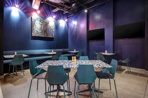 A restaurant with a blue interior, multiple tables and chairs, and a large abstract painting on the wall. - Aloft by Marriott Oklahoma City Downtown - Bricktown (Oklahoma City)