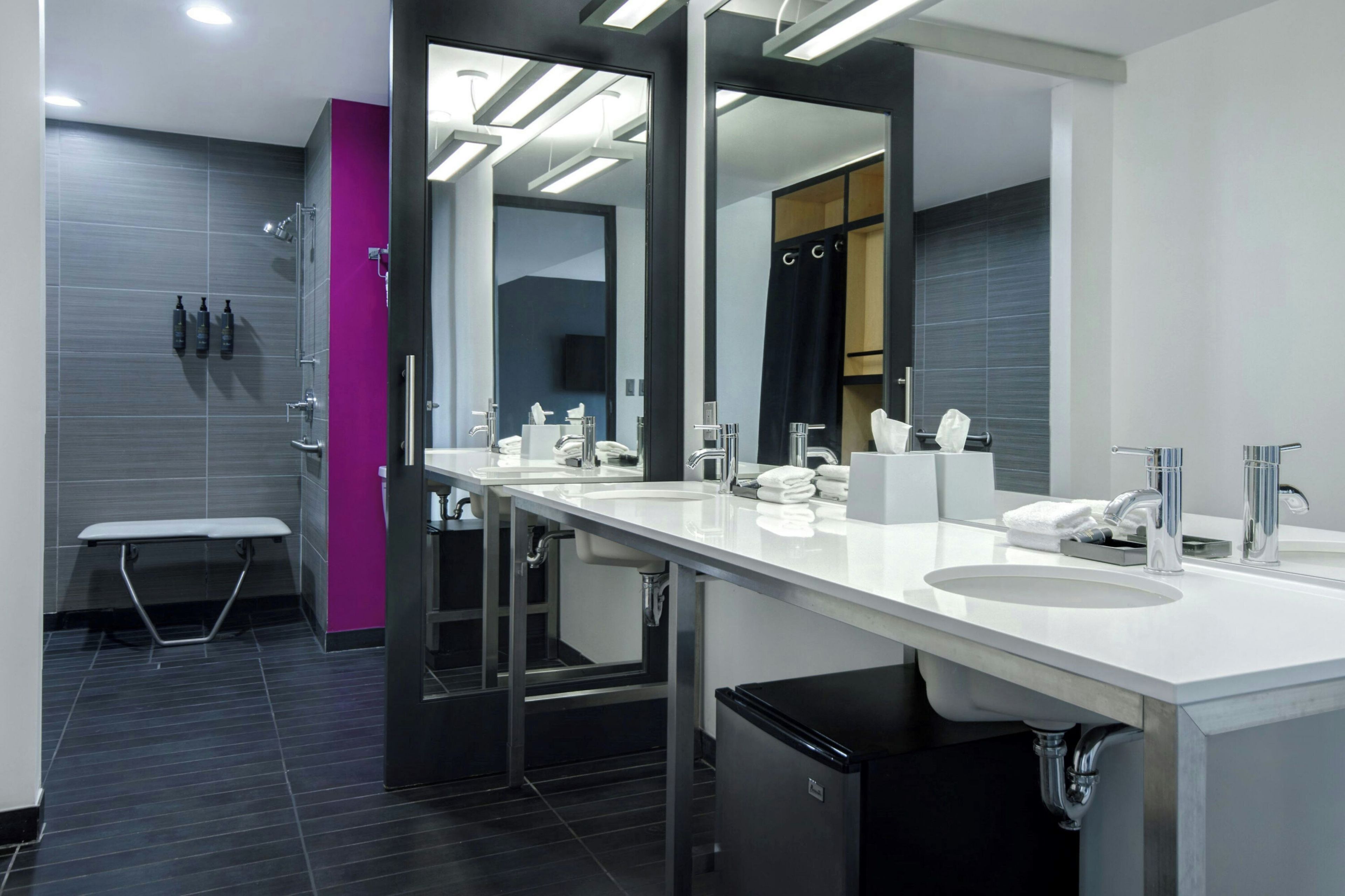 A modern bathroom with dual sinks, a large mirror, and a shower area.