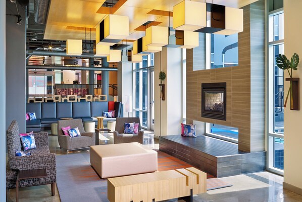 Un vestíbulo moderno con chimenea, zonas de estar y un amplio ventanal con vistas al exterior.