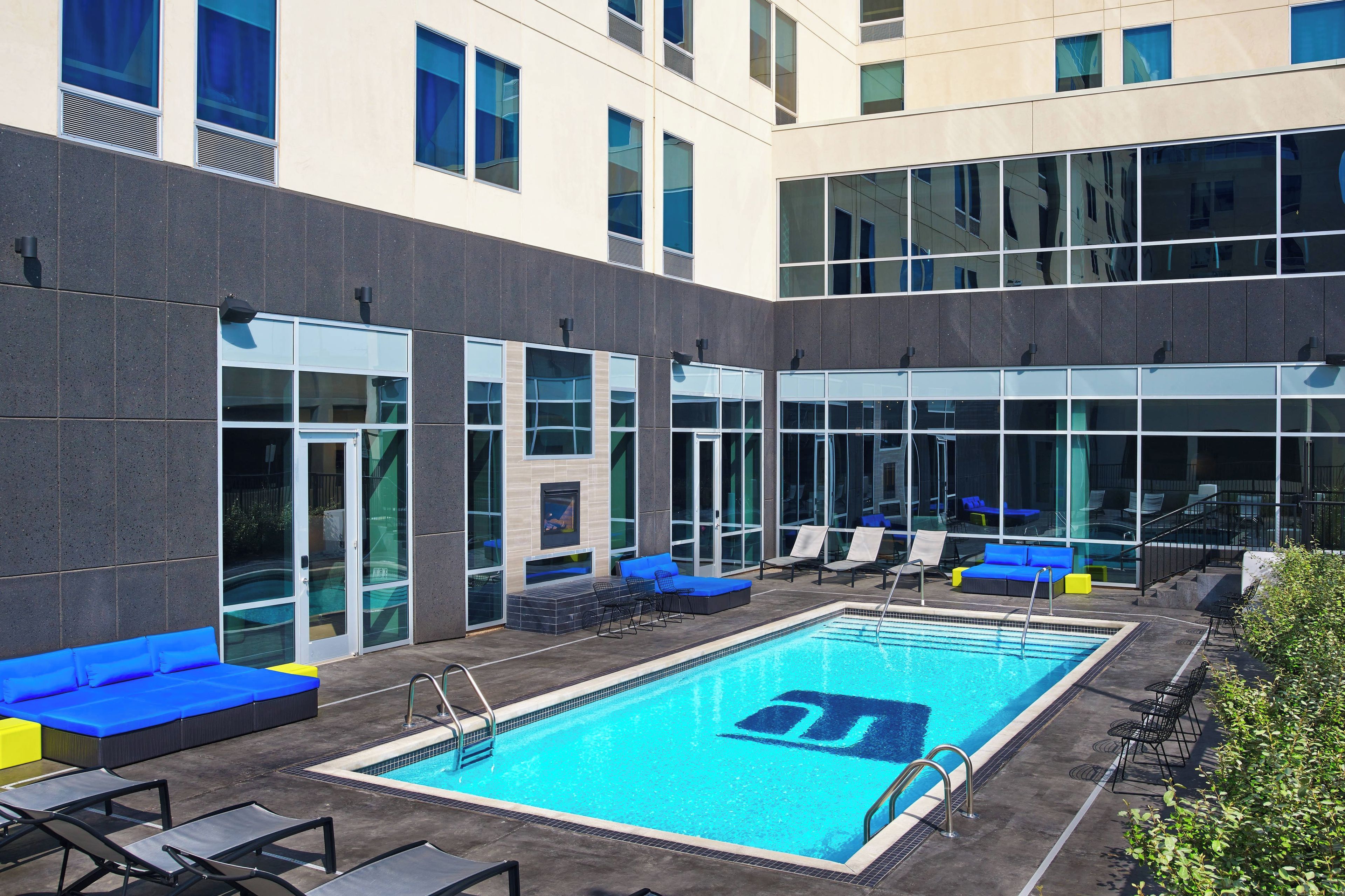 Área de piscina no terraço com espreguiçadeiras e um sofá azul.