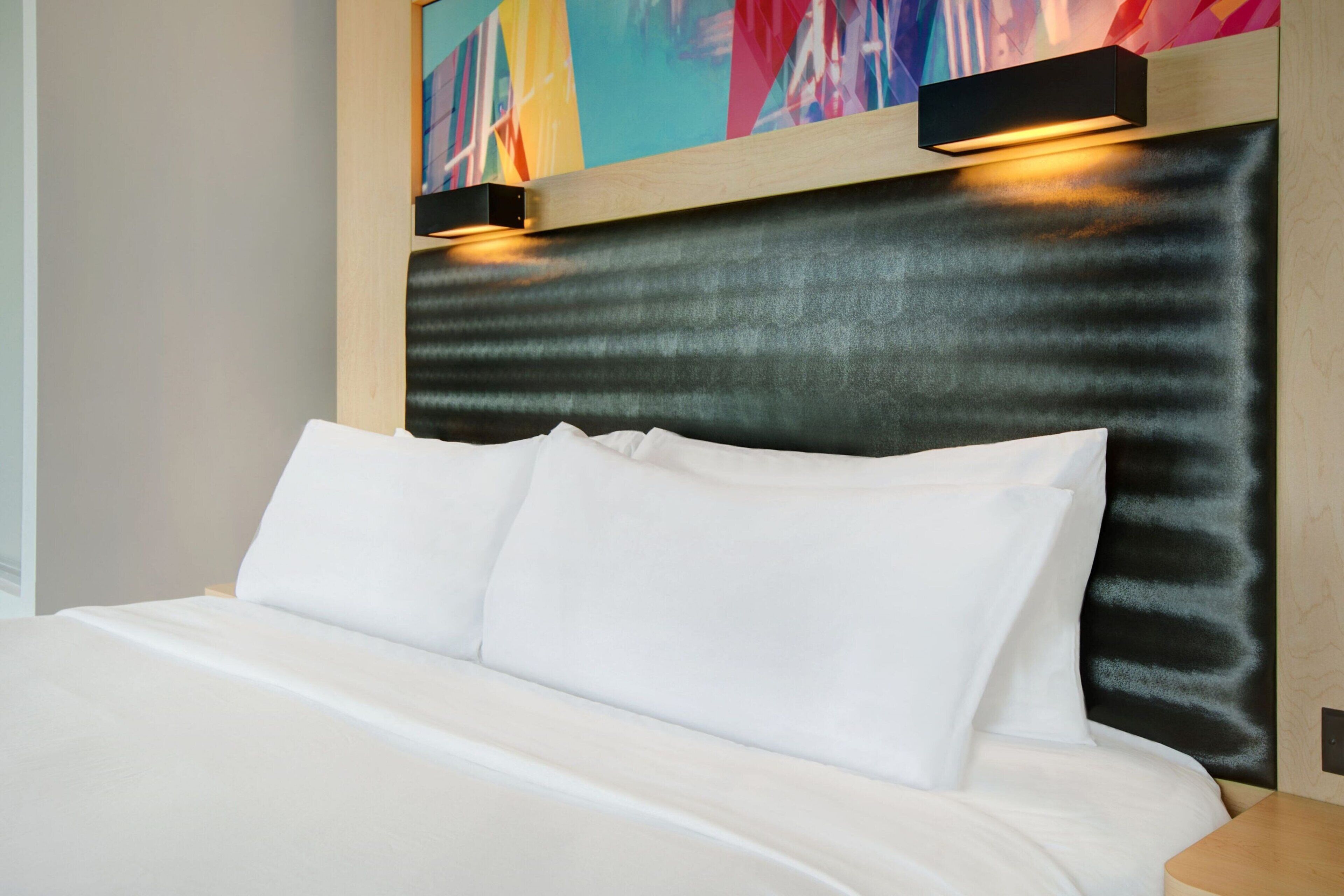 Una cama bien hecha con sábanas blancas en una habitación de hotel moderna.