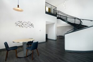 A modern interior with a round table and chairs, a spiral staircase, and a geometric wall art piece. - Aloft by Marriott Oklahoma City Downtown - Bricktown (Oklahoma City)
