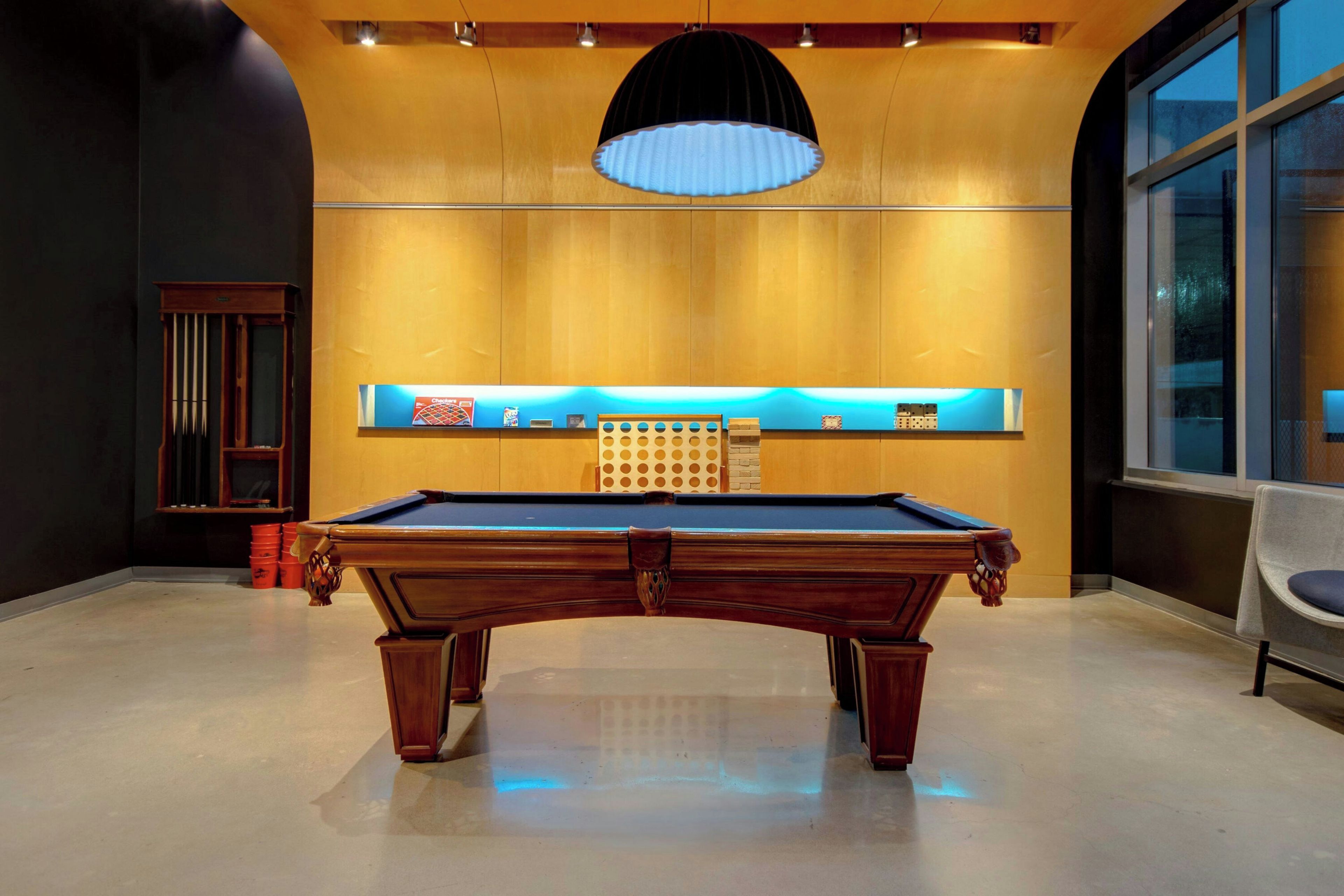 A pool table in a room with a wooden ceiling and a large window.