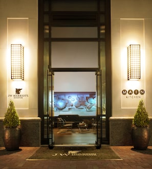 The JW Marriott Houston's main entrance with a modern design, including a glass door, a reception area with a sofa and chairs, and a decorative wall art above the entrance. - JW Marriott Houston Downtown (Houston)