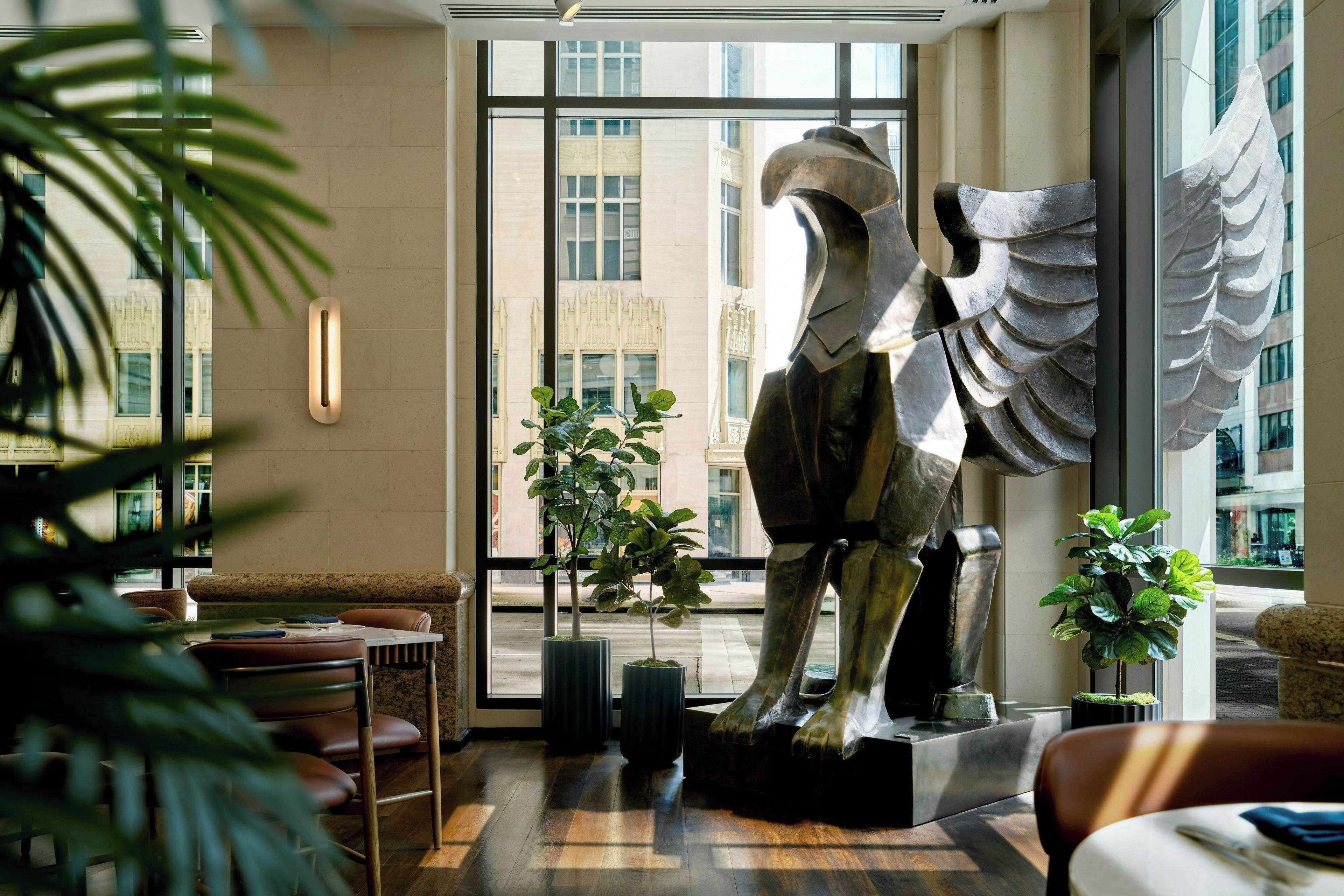 Un interior moderno con una gran escultura, una zona de estar y ventanas amplias.